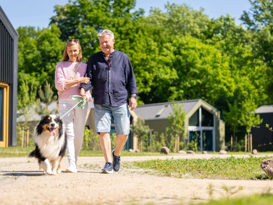 Een stel wandelt met hun hond over een zandpad op het huisdiervriendelijke vakantiepark Olde Kottink.