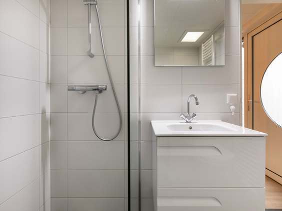 De moderne, witte badkamer in een bungalow op Parc de Berkenhorst, met een inloopdouche en wastafel.