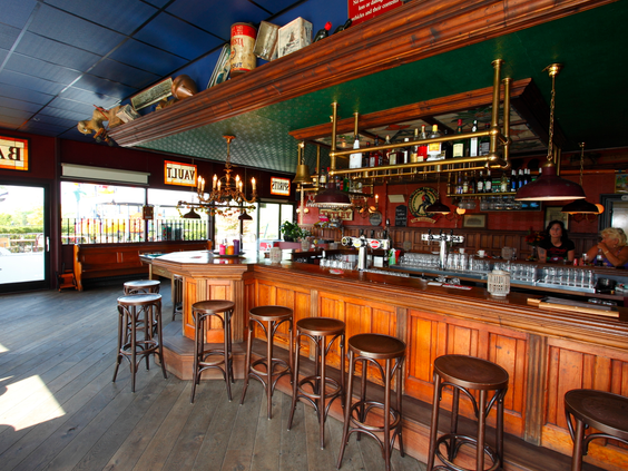 Het gezellige, authentieke interieur van het eetcafé op Parc de IJsselhoeve, met een klassieke houten bar en krukken.