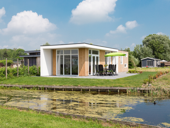 Een luxe en modern vakantiehuis met houten details en grote ramen, gelegen direct aan een vijver op Parc de IJsselhoeve.