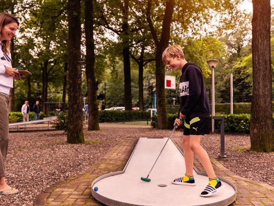 Een jongen speelt midgetgolf op de avontuurlijke midgetgolfbaan in de bossen van Parc Heihaas.