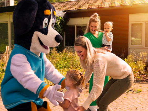 Mascotte Senn van Parc Heihaas begroet een gezin met jonge kinderen tijdens een meet & greet.