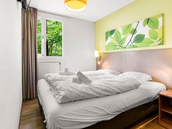 De comfortabele tweepersoons slaapkamer in een cottage op Parc Heihaas, met uitzicht op het bos.