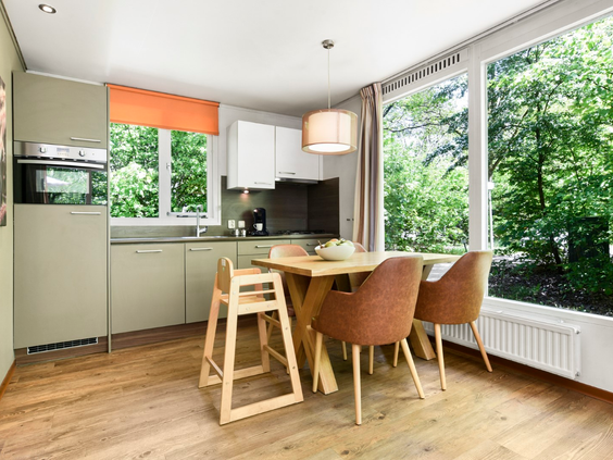De moderne open keuken en eethoek in een cottage op Parc Heihaas, met uitzicht op het groene bos.