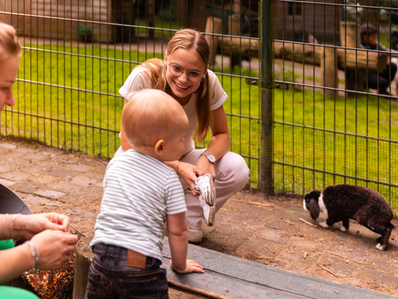 Een baby en moeder kijken naar een cavia op de gezellige kinderboerderij van Parc Heihaas.