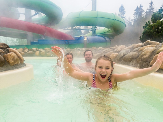 Een blij meisje en haar familie laten zich meevoeren door de stroomversnelling van de wildwaterbaan in de buitenlucht bij Aqua Mundo, Center Parcs Park Allgäu.