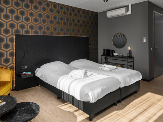 Stijlvolle en moderne hotelkamer in Roompot Klein Vink met een comfortabel tweepersoonsbed en donkere, sfeervolle inrichting.