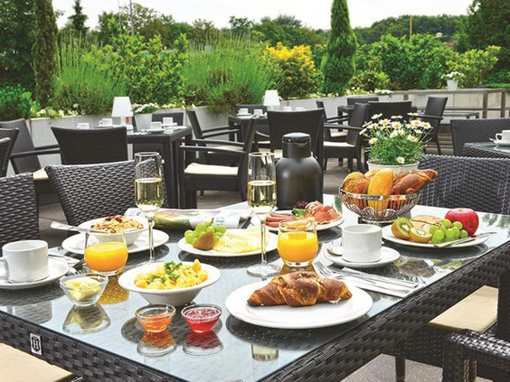 Een uitgebreid ontbijt geserveerd op het zonnige terras van Parkhotel Oberhausen, met opties voor het hele gezin.