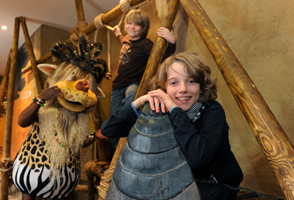 Twee lachende jongens poseren bij een Afrikaans standbeeld in het themahotel Matamba in attractiepark Phantasialand.