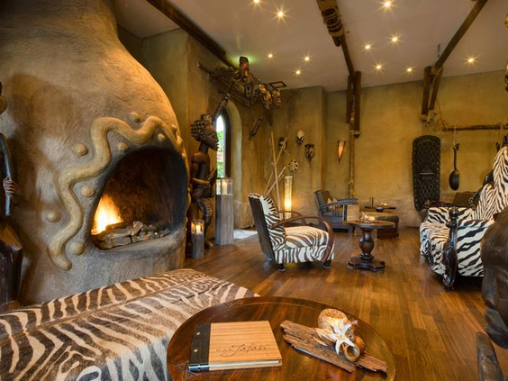 Sfeervolle lounge van Hotel Matamba in Phantasialand met meubels met zebraprint en een grote, unieke open haard.