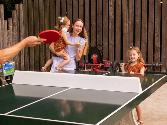 Een gezin speelt samen een potje tafeltennis bij een outdoor pingpongtafel op Vakantiepark Port Greve.