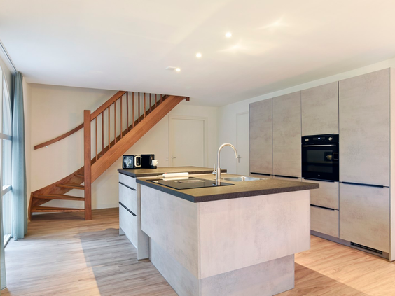 De moderne open keuken met een kookeiland en inbouwapparatuur in een luxe vakantiewoning op Port Greve.