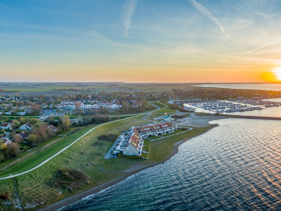 Panoramische luchtfoto van Vakantiepark Port Greve en de jachthaven tijdens een prachtige zonsondergang, met de vakantiehuizen aan het water.