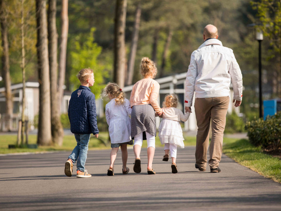 Een gezin met opa en oma wandelt over een pad op het bosrijke Recreatiepark Beekbergen op de Veluwe.