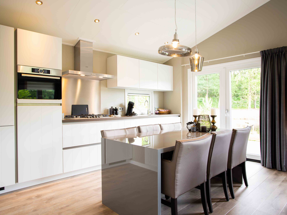 De moderne open keuken met een kookeiland en eethoek in een luxe vakantiewoning op Recreatiepark Beekbergen.