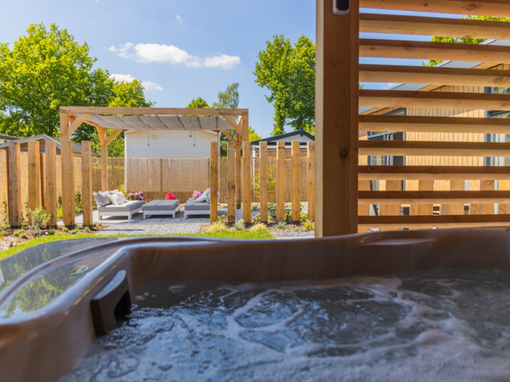 Een bubbelende privé-jacuzzi in de omheinde tuin van een luxe wellness-accommodatie op Recreatiepark de Boshoek.