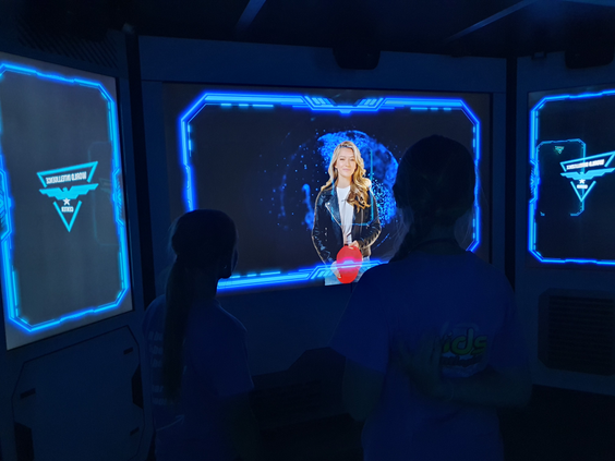 Twee kinderen werken samen en lossen een mysterie op in de interactieve X-Cube escaperoom van Recreatiepark de Boshoek, waarbij ze naar de touchscreens kijken.