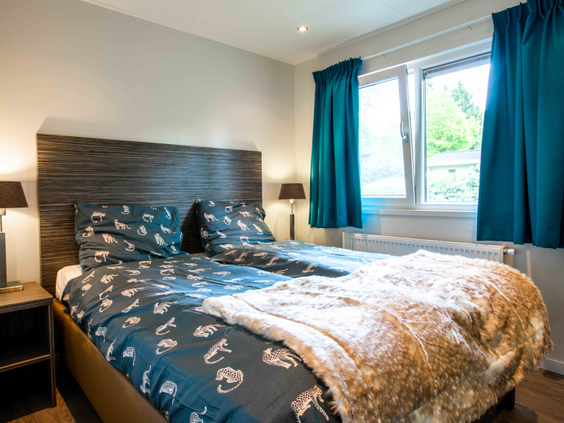 Een stijlvol ingerichte slaapkamer met een comfortabel opgemaakt tweepersoonsbed in een vakantiehuis op Het Esmeer.