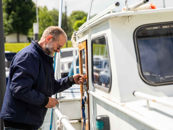 Een man stapt aan boord van zijn boot die is aangemeerd in de jachthaven van Recreatiepark Het Esmeer.
