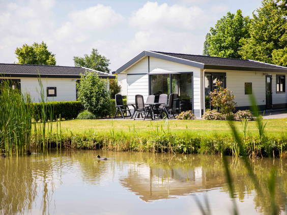 Een modern wit vakantiehuisje met een gemeubileerd terras, gelegen direct aan de waterkant op Recreatiepark Het Esmeer.