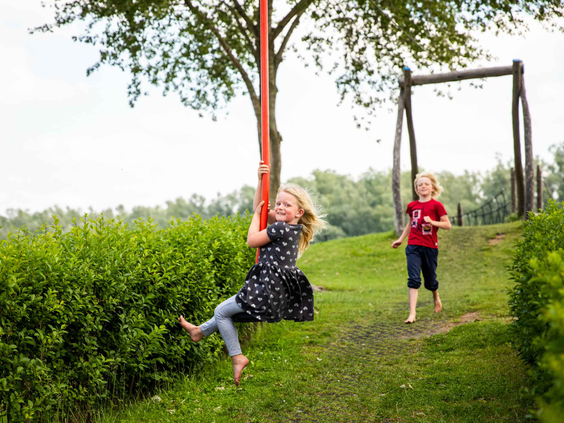 Een meisje beleeft plezier en zoeft met een lach op haar gezicht van de kabelbaan in de speeltuin.