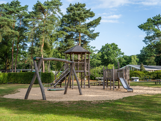 Groot houten klimtoestel met glijbaan in de buitenspeeltuin van Recreatiepark 't Gelloo.