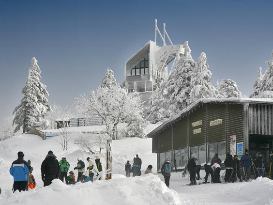 Het besneeuwde bergstation van de Wurmberg kabelbaan in Braunlage, met skiërs en wintersporters op de voorgrond.