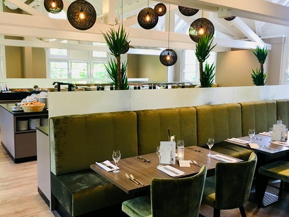 De lichte en modern ingerichte ontbijtzaal van het Relexa Hotel in Braunlage met comfortabele groene banken.