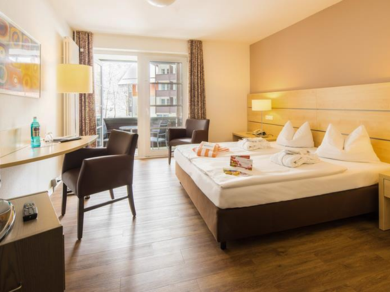 Een comfortabele en ruime hotelkamer in het Relexa Hotel in Braunlage, met een opgemaakt bed en een deur naar het balkon.
