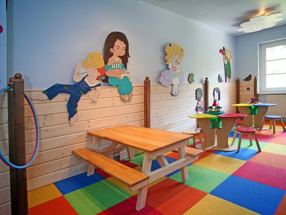 De vrolijke speelhoek voor kinderen in het Relexa Hotel, met een picknicktafel, zachte speelmatten en leuke tekeningen aan de muur.