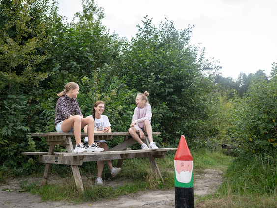 Kinderen pauzeren aan een picknicktafel langs het Kabouterpad in de Schoorlse Duinen, met een kabouterpaaltje ernaast.
