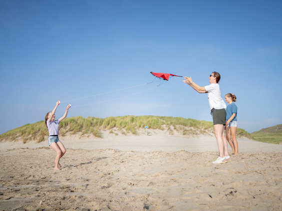 Twee kinderen laten samen een vlieger op op het brede zandstrand van Bergen aan Zee.