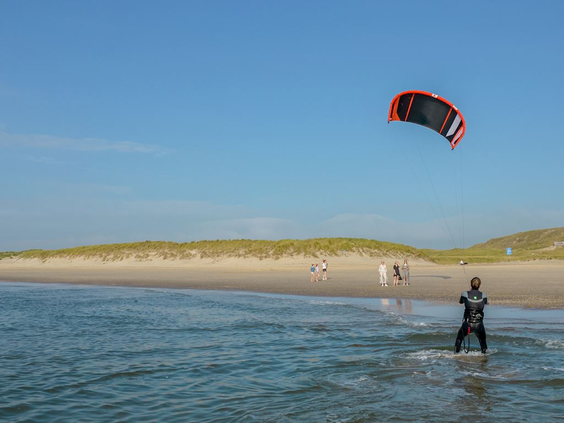 Een kitesurfer in actie op de golven van de Noordzee voor de kust van Bergen aan Zee.