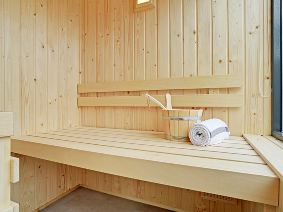 Het interieur van een houten privé-sauna in een vakantievilla op Residence Berger Duinen, met opgerolde handdoeken.