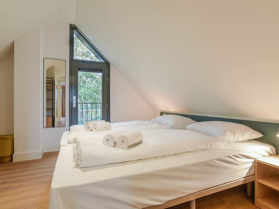 Een lichte, sfeervolle slaapkamer met een opgemaakt tweepersoonsbed in een vakantievilla op Residence Berger Duinen.