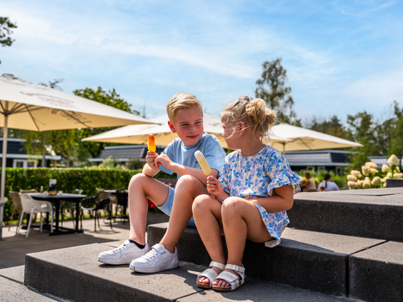 Twee kinderen zitten aan een tafel op het terras van het restaurant op Residence Lichtenvoorde.