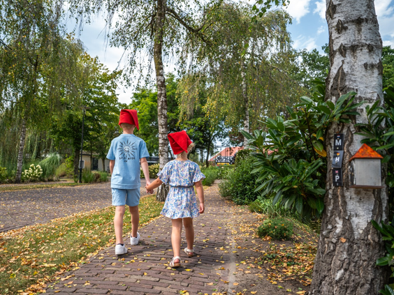 Twee kinderen met kaboutermutsen lopen over het kabouterpad op Residence Lichtenvoorde in de natuur.