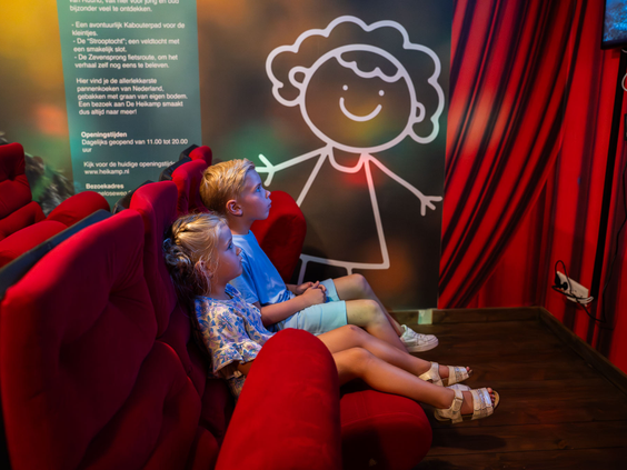 Kinderen zitten in het kleine theater van de Kidsclub te kijken naar een show