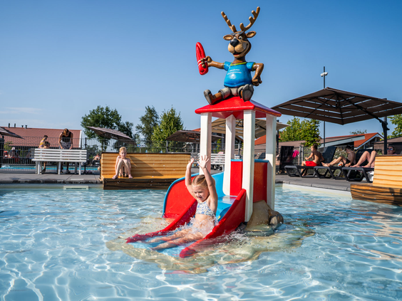 Kinderen spelen bij het watertoestel met glijbaan in het buitenzwembad van Residence Lichtenvoorde.