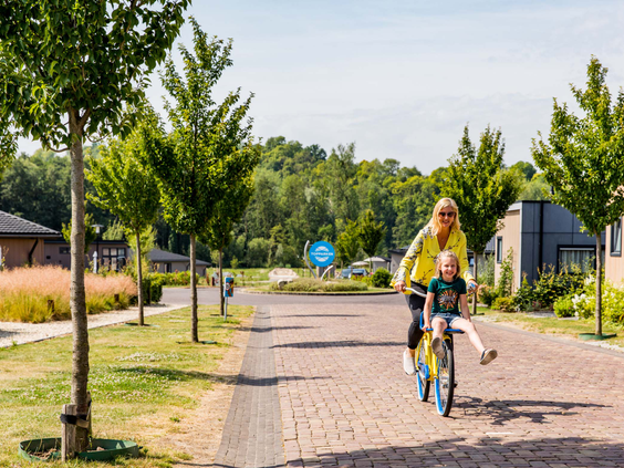 Een moeder en kind fietsen over het vakantiepark Residence Valkenburg voor een tocht door de Limburgse natuur.