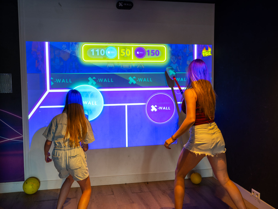 Kinderen spelen een interactief spel op een grote digitale wand in de gameroom op Residence Valkenburg.