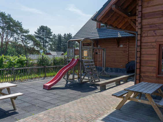 Een speeltuintje met een glijbaan en picknicktafels direct naast de houten brasserie op Resort Brunssummerheide.