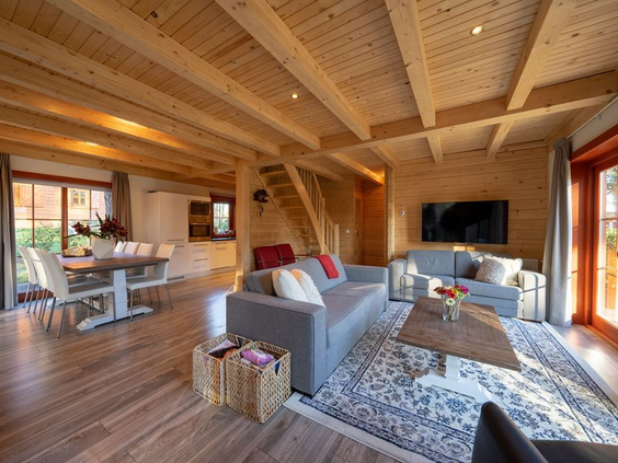 De sfeervolle en ruime woonkamer van een houten lodge op Resort Brunssummerheide, met een gezellige zithoek en houten balkenplafond.