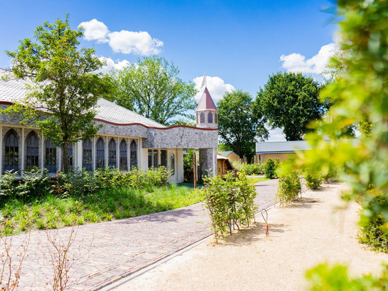 Het unieke, kasteelachtige gebouw van Resort Kaatsheuvel, omringd door groene tuinen en wandelpaden.