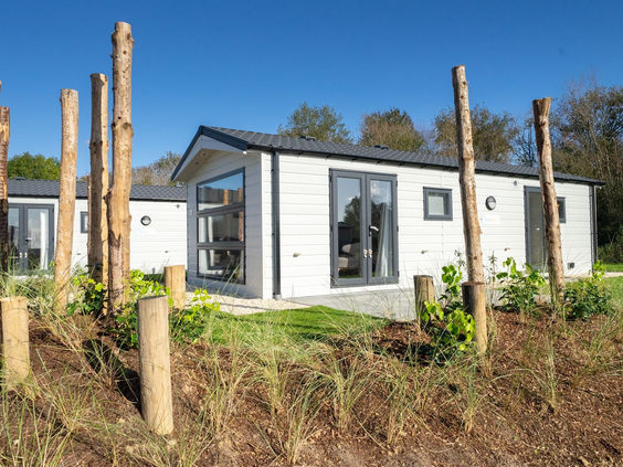 Een moderne, witte Duin Lodge vakantiewoning op Resort Kaatsheuvel, gelegen in een natuurlijk aangelegd duinlandschap.