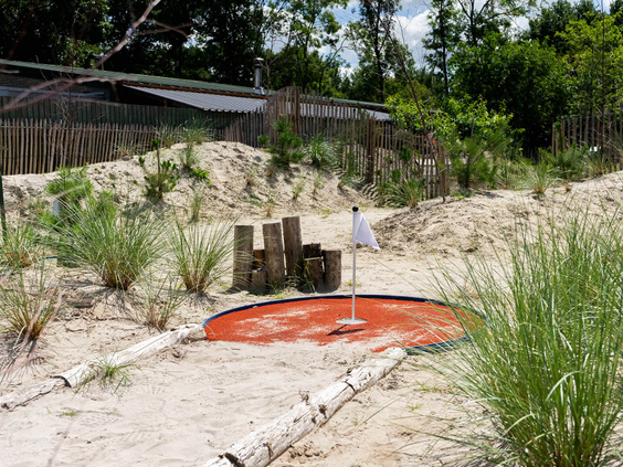 Een uitdagende hole op de avontuurlijke midgetgolfbaan van Resort Kaatsheuvel, gelegen in een zanderig landschap.