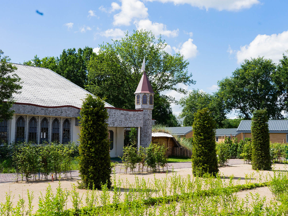De strak aangelegde tuin met jonge planten voor het kasteelachtige gebouw van Resort Kaatsheuvel.