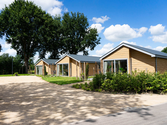 Drie moderne vakantiehuizen met een houten gevel en grote ramen, gelegen aan een pad op Resort Kaatsheuvel.