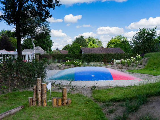 Een grote, ronde airtrampoline met de kleuren rood, blauw en groen in de speeltuin van Resort Kaatsheuvel.