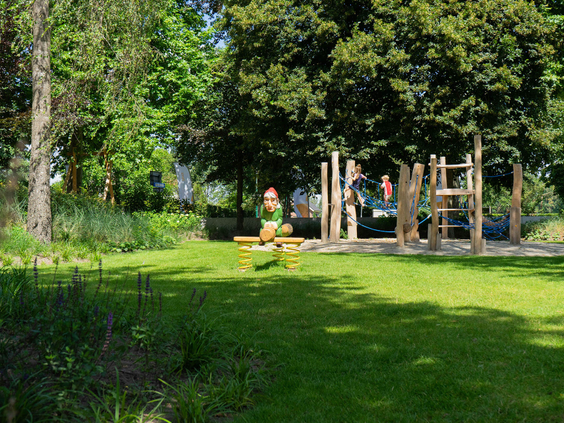 Een houten wipwap en een klimtoestel in de groene, ruim opgezette speeltuin van Resort Kaatsheuvel.